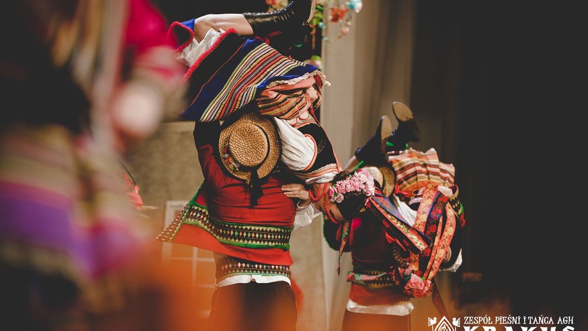 Photo of a folk group in traditional folk costumes performing on stage.