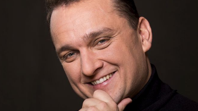 Photo of the artist on a black background.