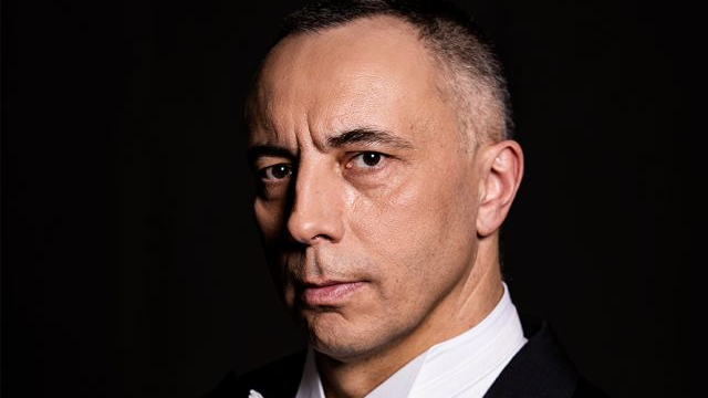 Photo of the artist on a black background.