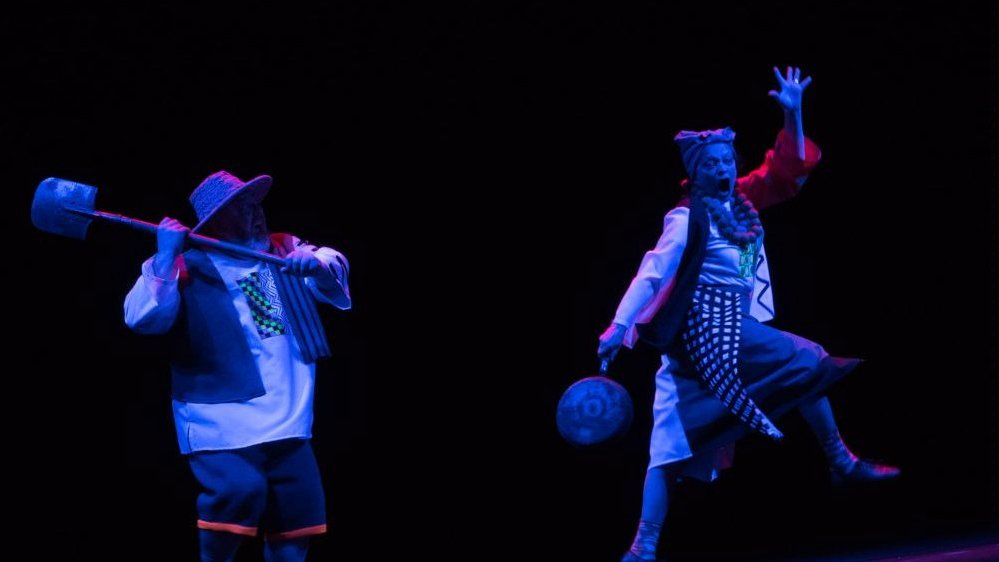 Photo from the performance - two actors on stage, black background.