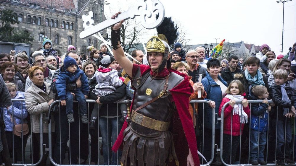 Photo from one of the previous St. Martin parade: picture of a men dressed as St. Martin and holding a big key in his hand. People watching the show in the background. - grafika artykułu