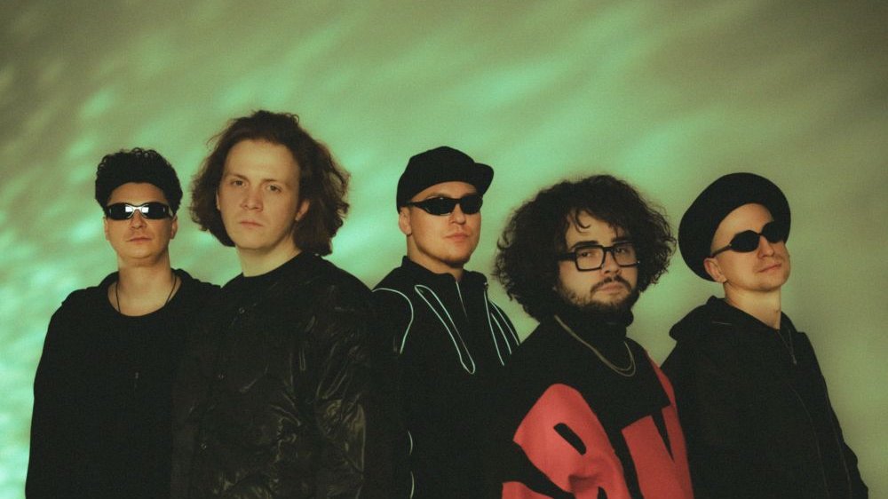 Photo of a band - five men on a green background. - grafika artykułu