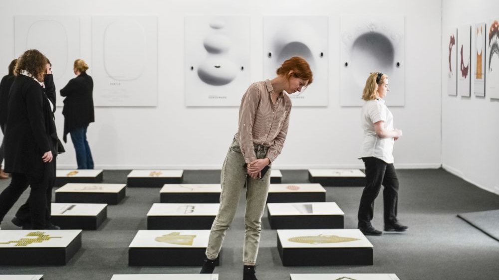 Photo of the exhibition hall and a few people watching the pictures.