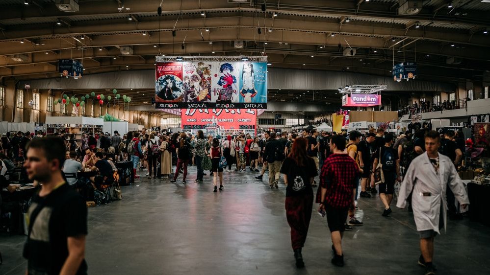 Photo of an exhibition hall fulfilled with people walking around.