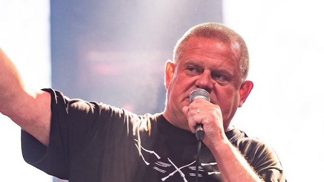 Photo of Kazik Staszewski - frontman of the Kult band - who is singing to a microphone.