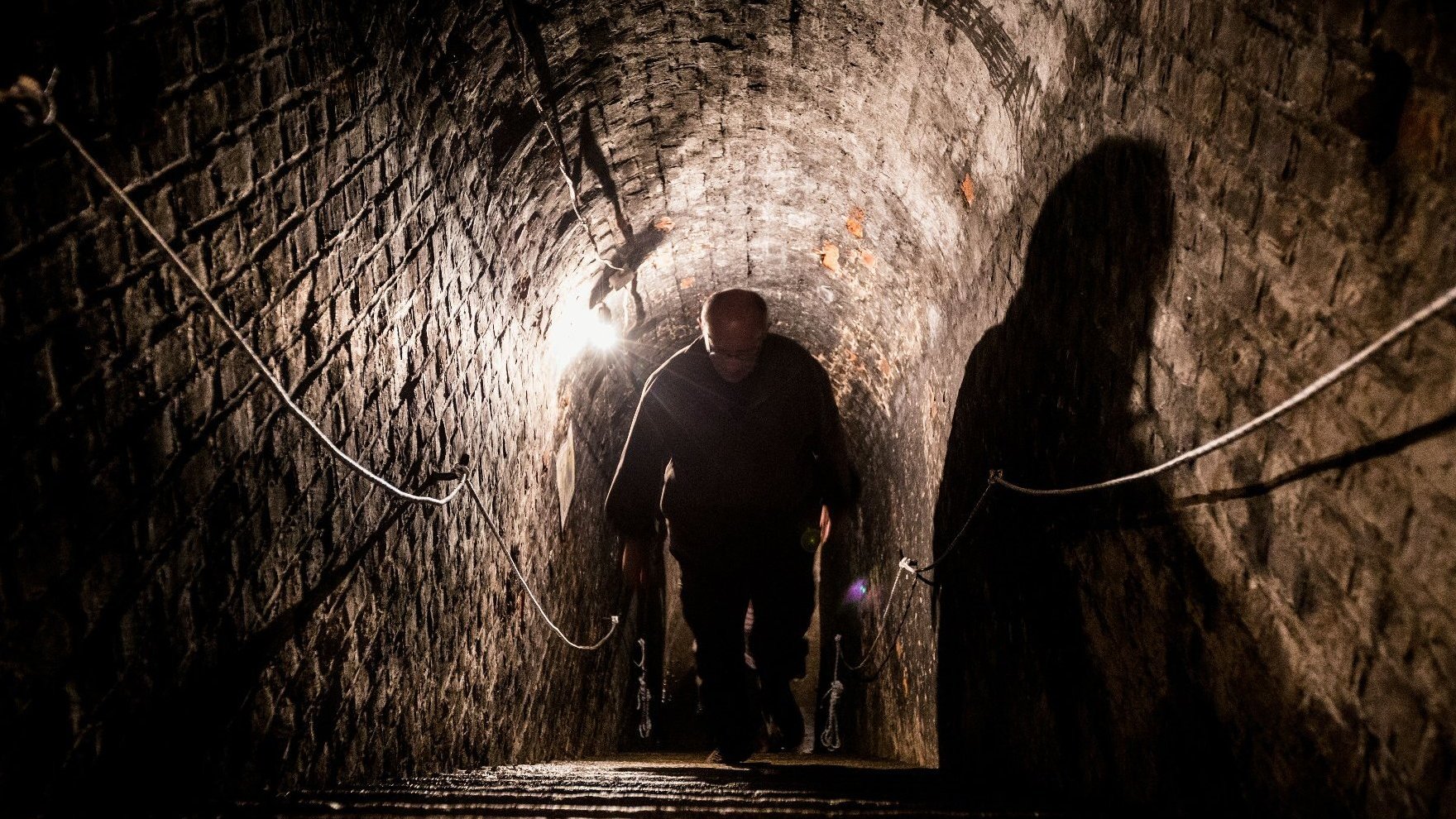 Underground corridor. The man is walking up the steep stairs.