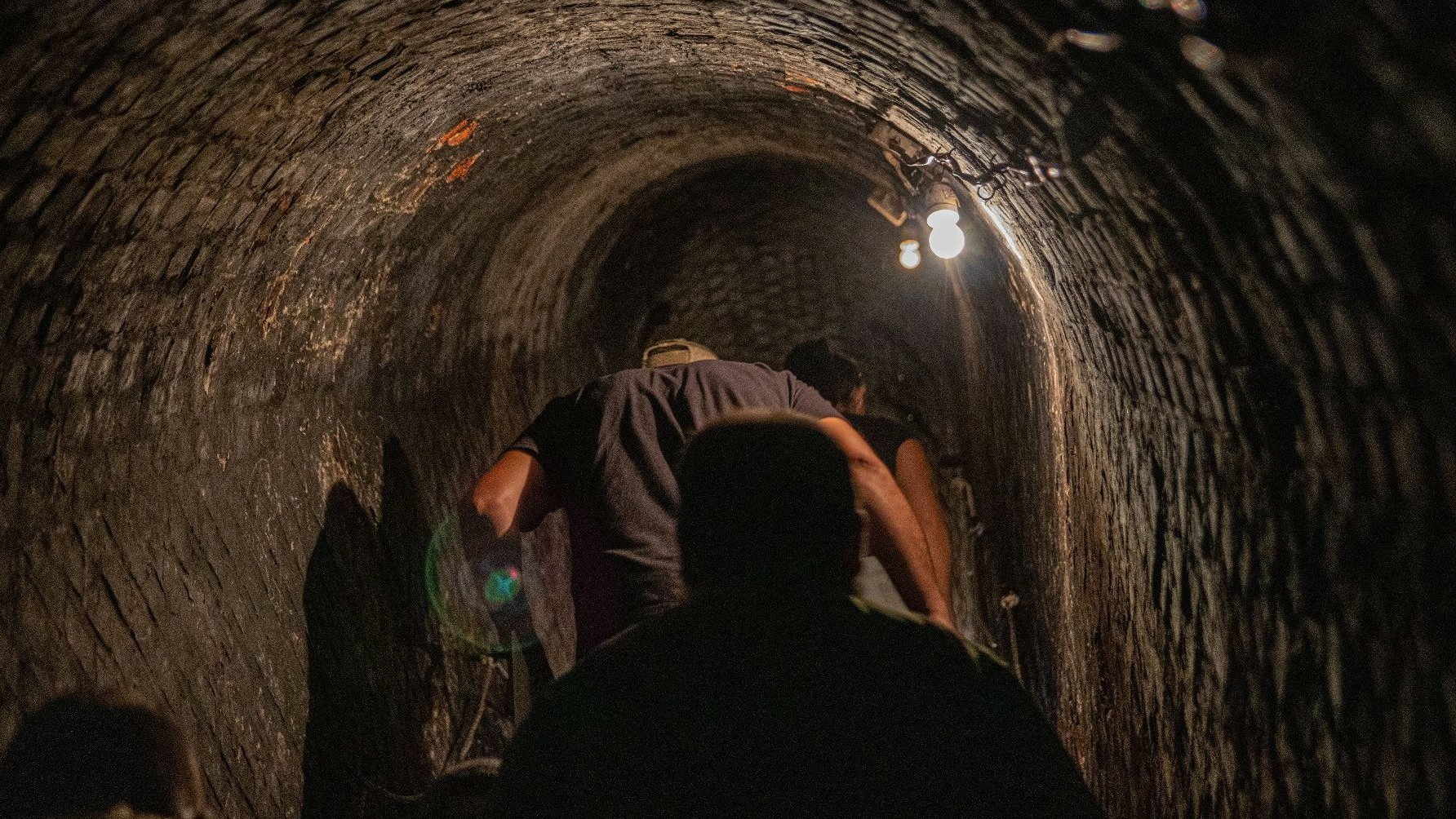 An underground corridor in which several people are walking with their backs to the camera.
