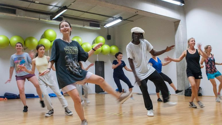 A group of dancing people in similar poses. As a background - green balls hanging at the wall.