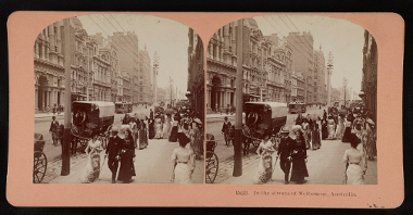 Stereophotograph of a street in sepia colours: people walking along the street in old-fashioned clothes, horsedriven cab on the street and a lane of buildings on the left.