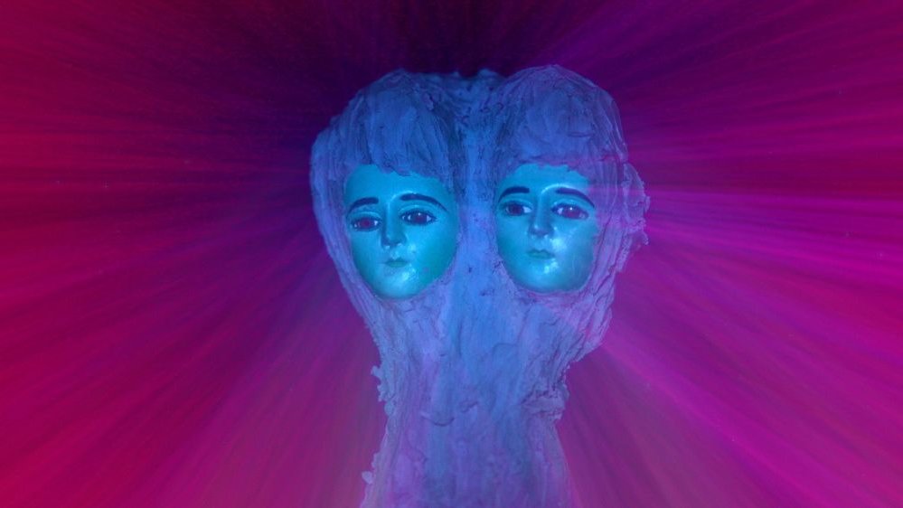 Faces of two dolls with long blue hair, connected to each other. Purple and burgundy background. - grafika artykułu