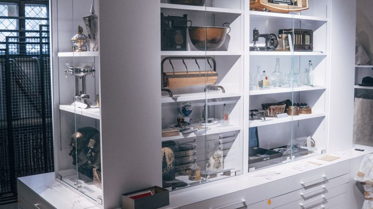 White bookcase with shelves and drawers, exhibits on the shelves.
