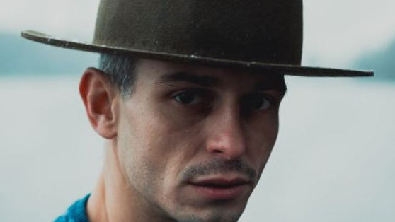Photo of a young man wearing a hat. Blue background.