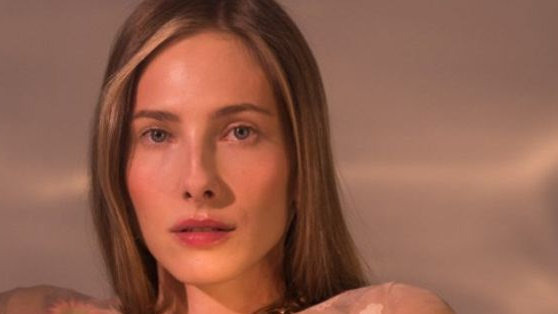 A photo of the face of a young woman, with fair, long hair, of delicate beauty. The woman looks straight into the camera.