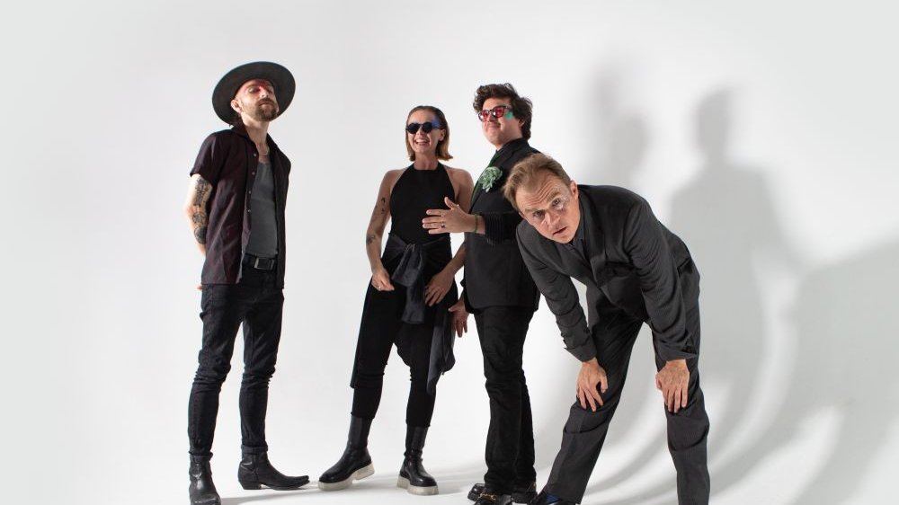 Photo of four people in different poses, dressed in black, on a white background.