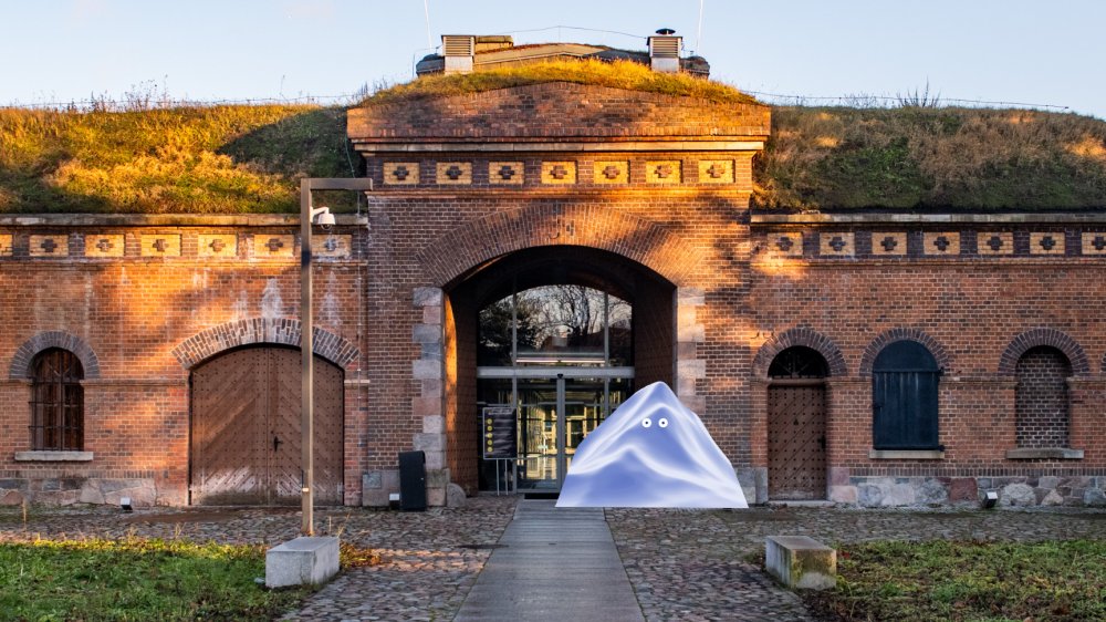 The fort building with a glass entrance gate. In front of the entrance there is a graphic depicting a triangular block of ice with eyes.