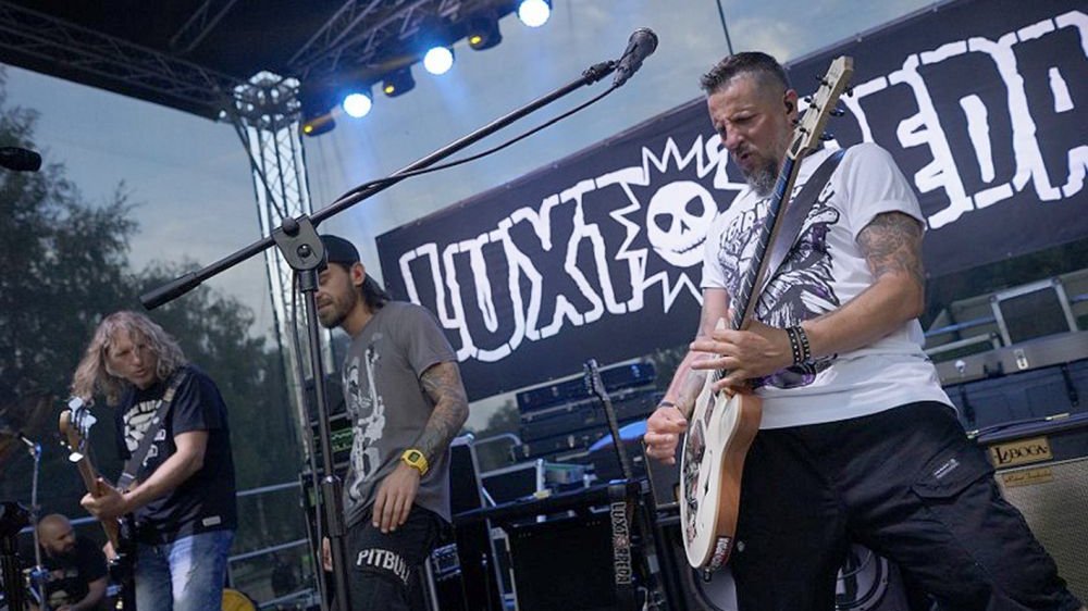 A band playing on stage, the name of the band in the background.