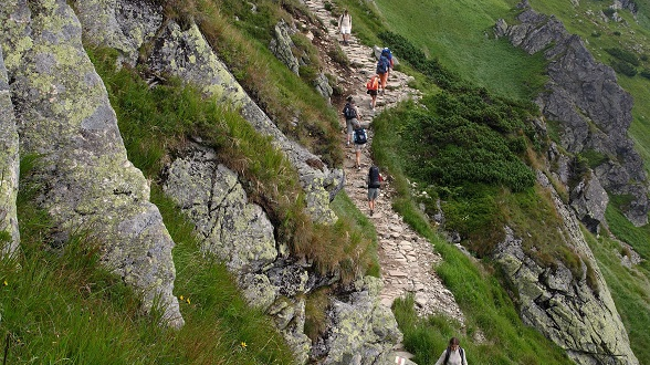 Mountain landscape. On the mountainside, along a stone path, several tourists.