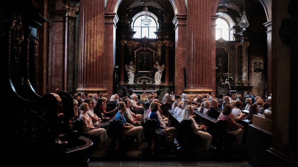 The interior of the parish church, where all the seats are occupied by people - concert goers. There is an atmosphere of concentration.