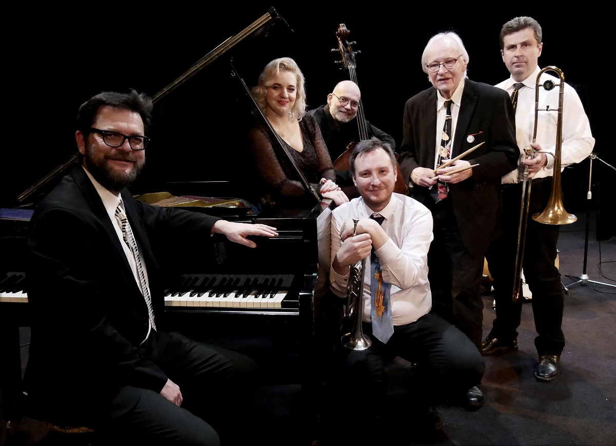 Photo of five men and one woman elegantly dressed. One of the men is sitting at a piano, the others are standing next to it. The men are holding musical instruments. - grafika artykułu