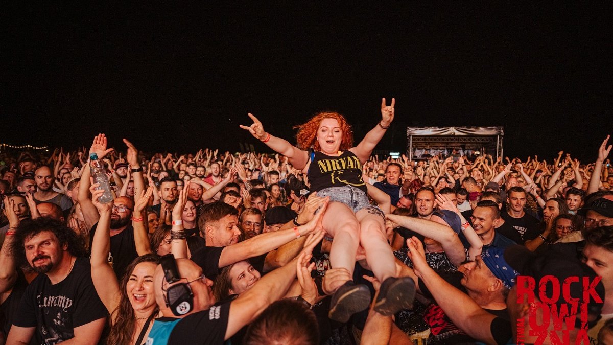 Crowd in front of the stage. One of the girls, redhead and wearing a Nirvana t-shirt, is being carried by people in their arms, above their heads.