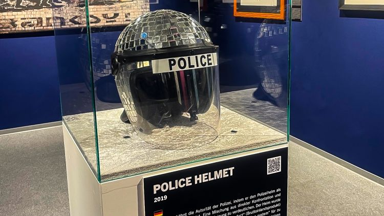 Police helmet in a glass case. The top of the helmet is covered with square glass, like a disco ball.