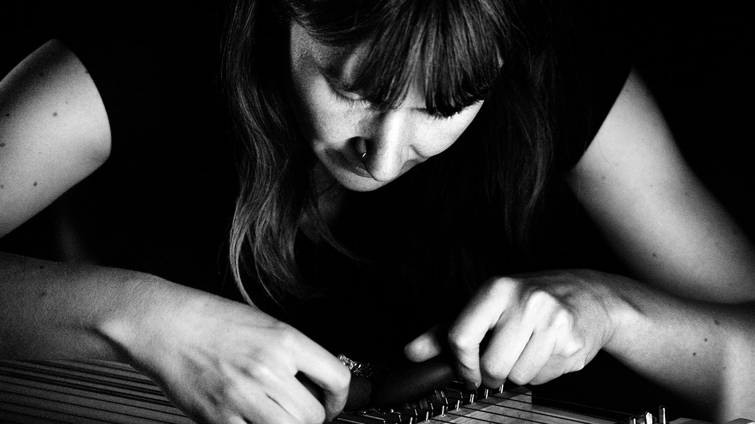 Black and white photo of a woman leaning over an instrument.