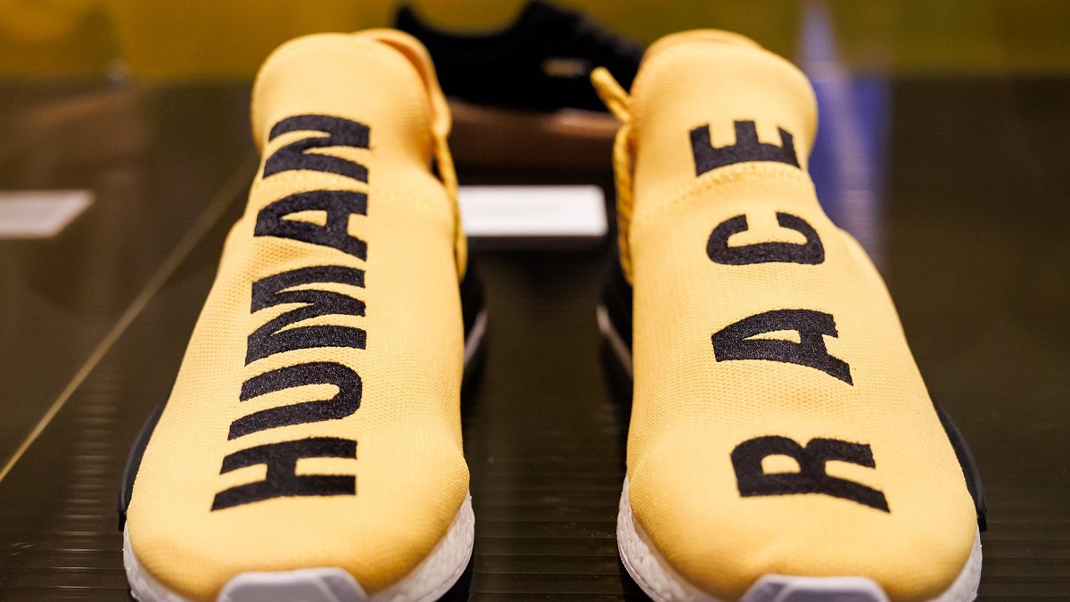 A pair of yellow sneakers. One has the word "human" written in black on it, the other has the word "race" written on it.