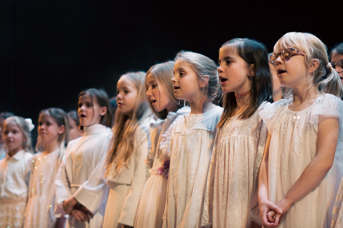 Photo of a few-year-old girls in white dresses, standing in a row and singing. - grafika artykułu