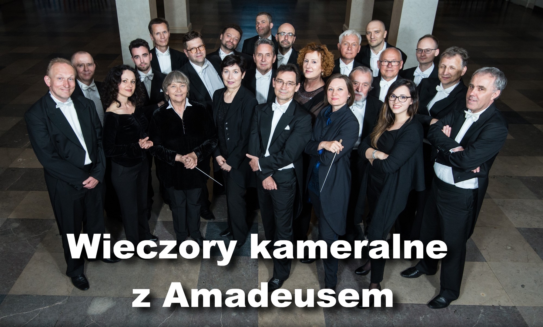 Photo of a group of people, members of Amadeus Orchestra, elegantly dressed. Two women are holding director's batons. - grafika artykułu