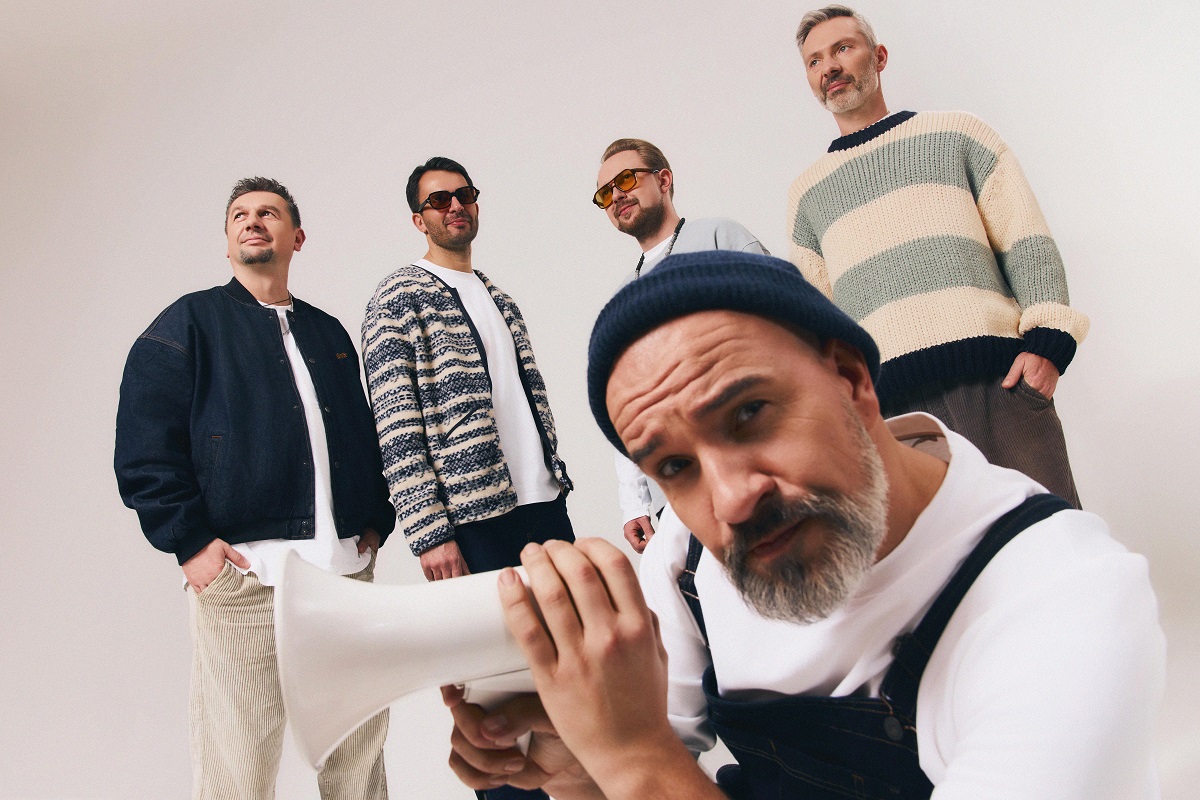 Five men, one of them, in front of the other four ones, is holding a megaphone. - grafika artykułu