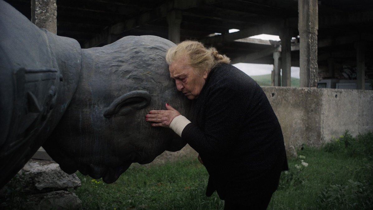 A man holding a stone head of a lying sculpture.