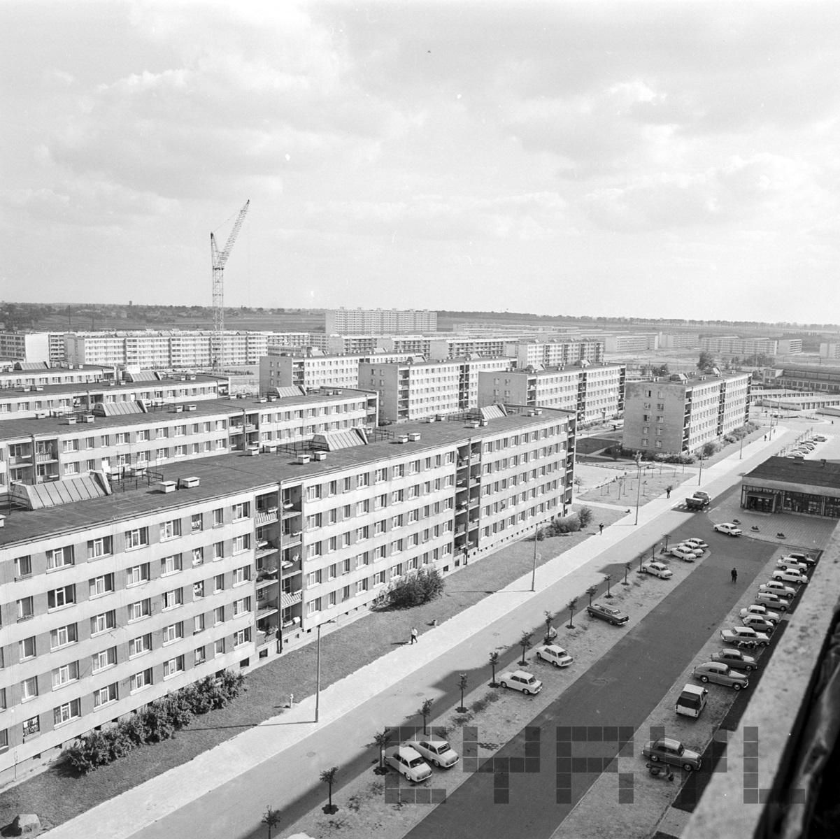 A black and white photo of a housing estate. A car park is in the foreground. - grafika artykułu
