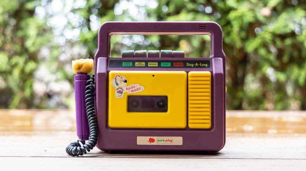 A small tape recorder in cheerful yellow and purple, with space for one cassette and an attached microphone