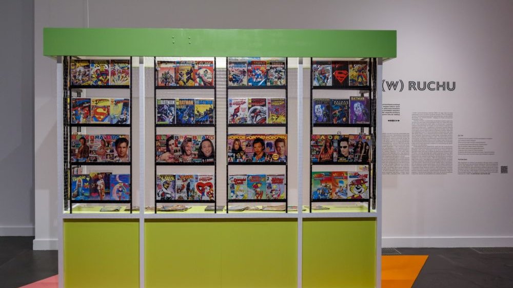 Colourful magazines displayed in display cases imitating a Ruch kiosk. Among them are "Bravo", "Popcorn" and comics in series.