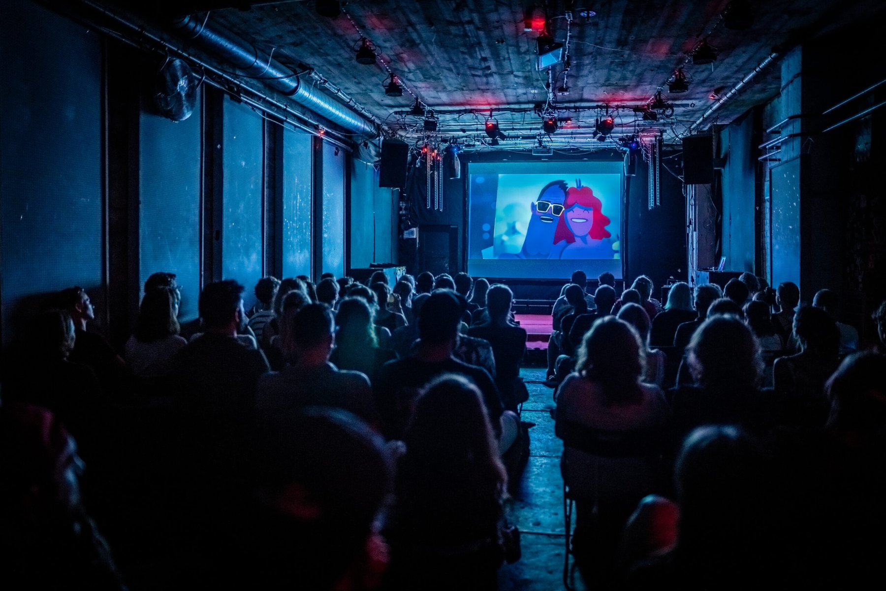 A darkened hall, full of viewers. An animated film is displayed on the screen. - grafika artykułu