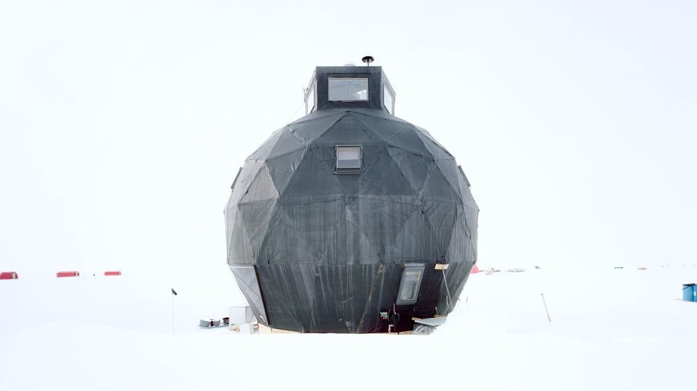 A black dome with geometric shapes, which may be a research station, stands in a snowy wasteland.