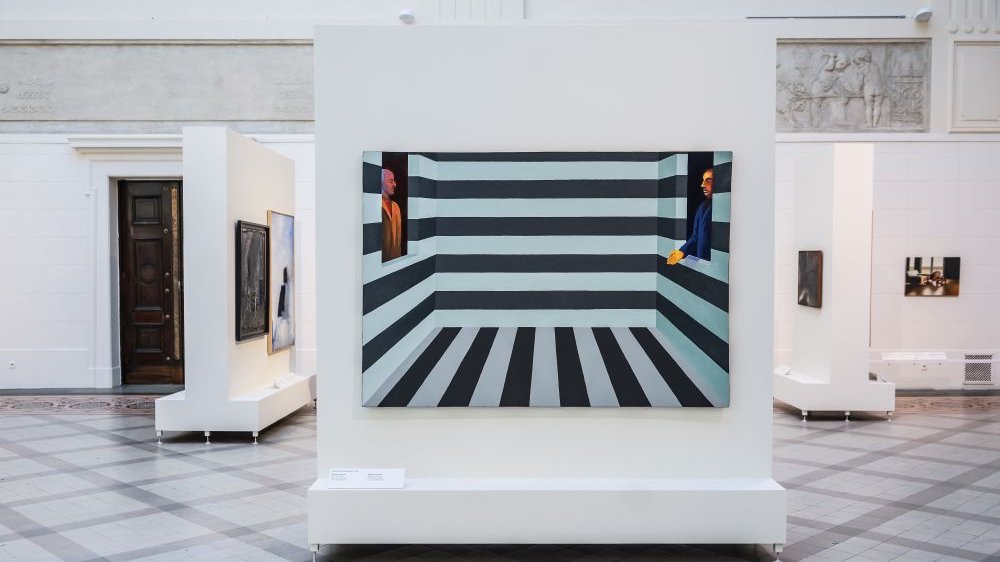 Paintings hanging on the white walls of the museum.