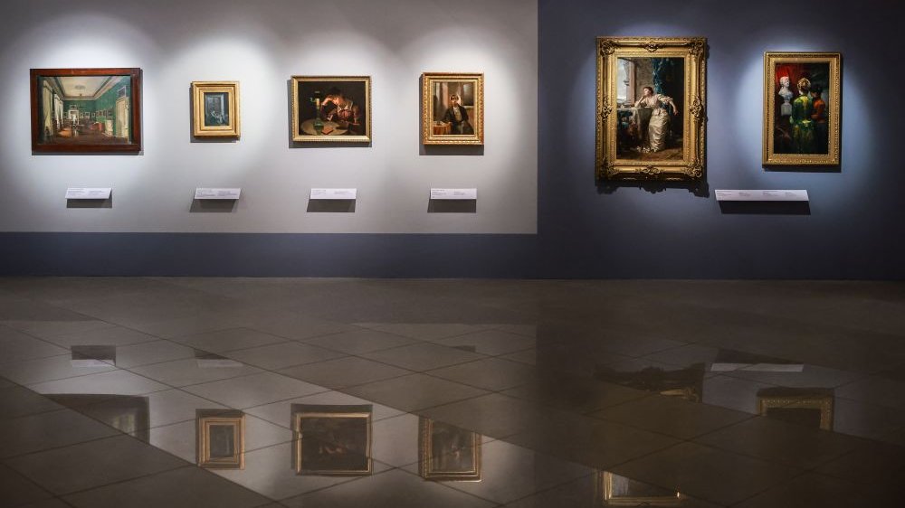 Pictures hang in frames on the wall, reflected in the shiny floor.