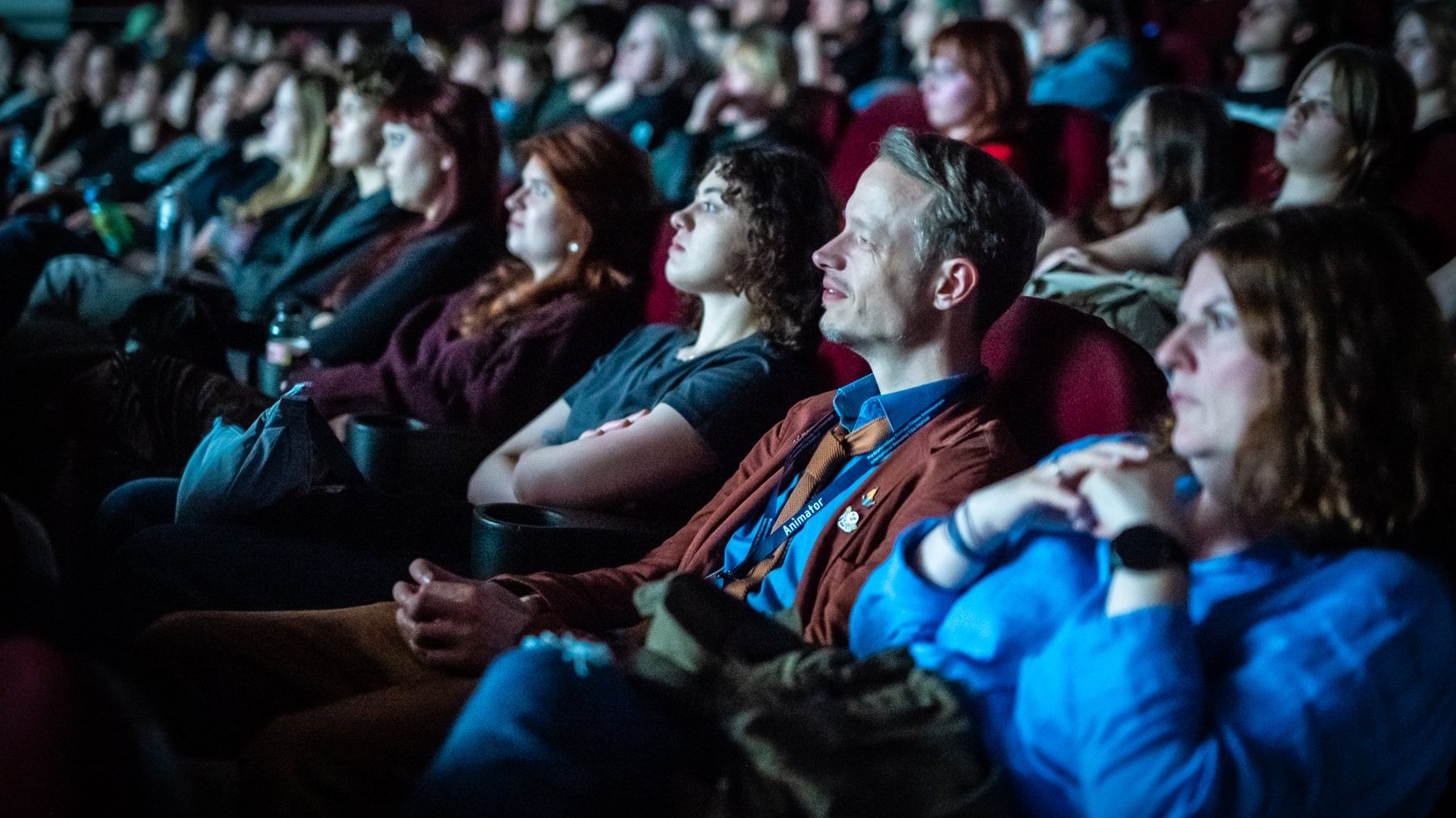 Viewers sit next to each other in several rows in the cinema hall.