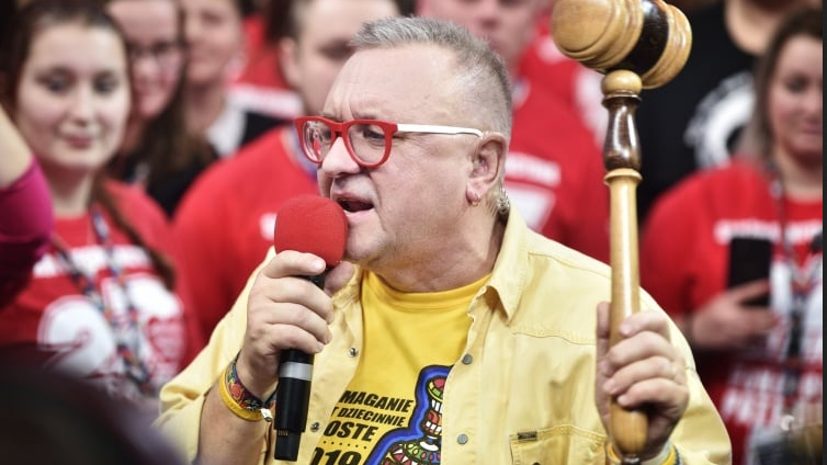 Jurek Owsiak with a microphone on stage during the final moments of the auction, holding the auction hammer in his hands.
