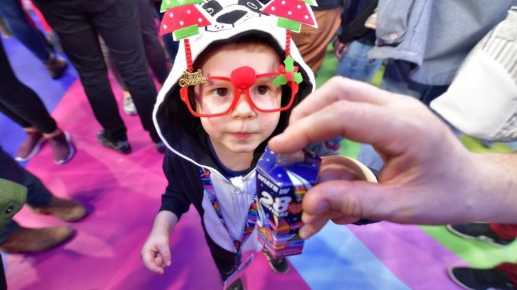 A little boy with funny glasses is a volunteer during the WOŚP finale, someone is just throwing a coin into his can.