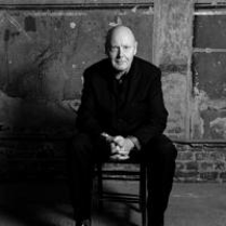 Black and white photo of the conductor - a sitting man with his hands folded