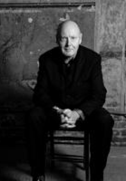 Black and white photo of the conductor - a sitting man with his hands folded