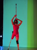 Scene from the performance - a disabled woman without one leg in red costume performing on stage