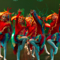 Photo of children in colourful clothes performing on stage.