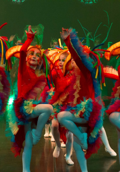 Photo of children in colourful clothes performing on stage.