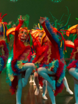 Photo of children in colourful clothes performing on stage.