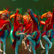 Photo of children in colourful clothes performing on stage.