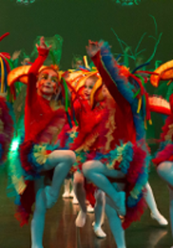 Photo of children in colourful clothes performing on stage.