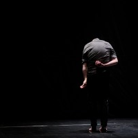 Photo from the performance - a man on a stage back to the audience.